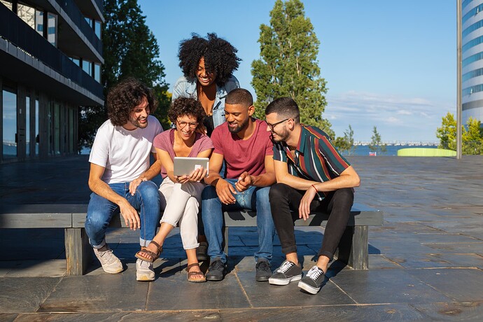 joyful-friends-watching-video-tablet-outdoors